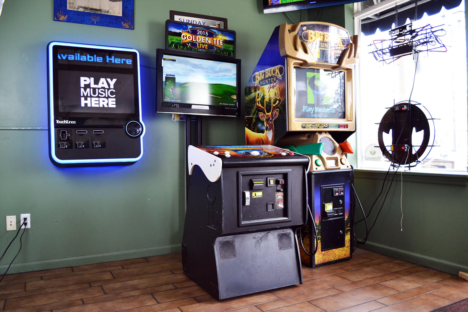 Golden Tee and Big Buck Hunter arcade cabinets beside a jukebox